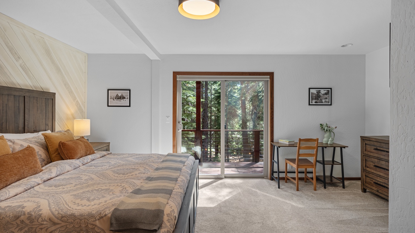 Wake up to towering redwoods framed by your private balcony doors. This peaceful bedroom blends rustic wood tones with soft linens, plus a quiet workspace for when inspiration strikes.