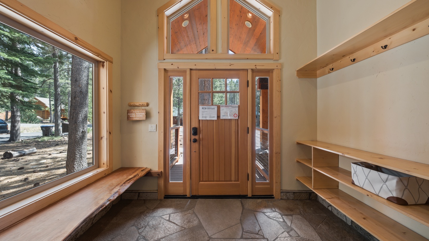 Step into your mountain retreat through this welcoming entryway with vaulted ceilings, warm wood accents, and scenic forest views greeting you at arrival.