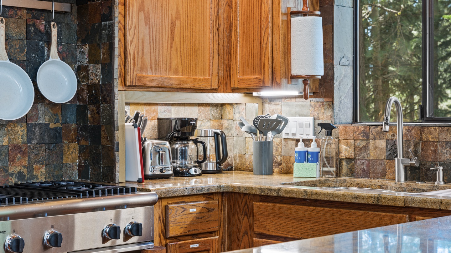 Step into your fully equipped kitchen where warm wood cabinetry meets natural light streaming through forest views. Granite counters, modern appliances, and thoughtful touches make cooking a pleasure during your stay.
