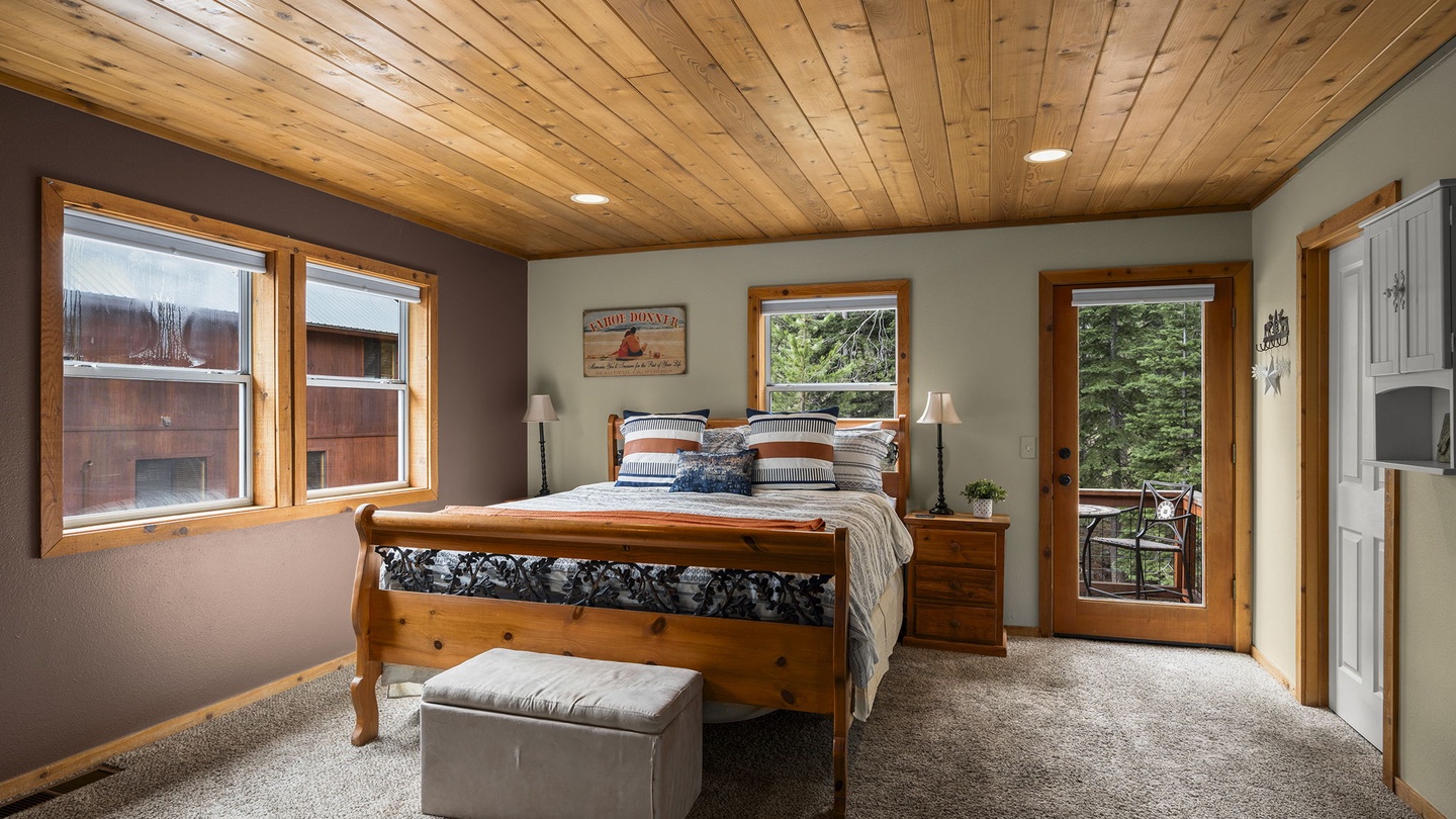 Unwind in your cozy retreat with stunning wood ceiling, comfortable bed, and peaceful forest views through your private balcony door.