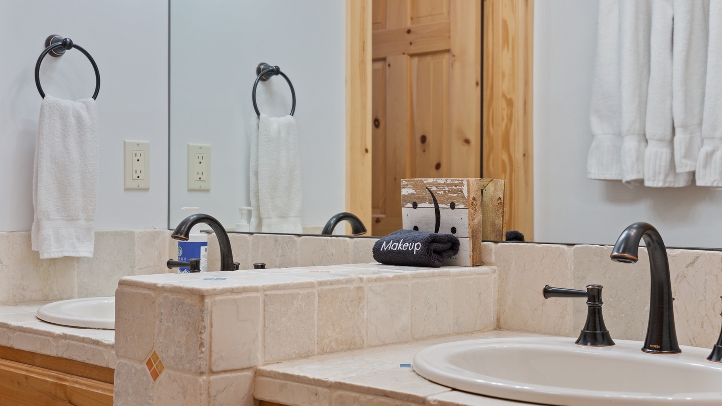 Freshen up at your spacious double vanity with plush towels and thoughtful amenities. The charming natural wood accents add warmth to your morning routine.