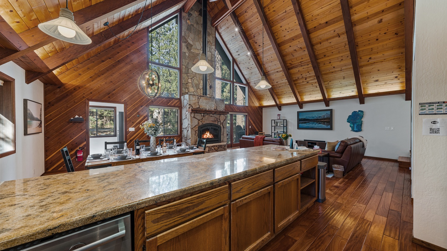 Soaring vaulted ceilings with exposed beams frame your open-concept retreat, where a stone fireplace anchors the space and a well-appointed kitchen invites you to gather and unwind in mountain comfort.