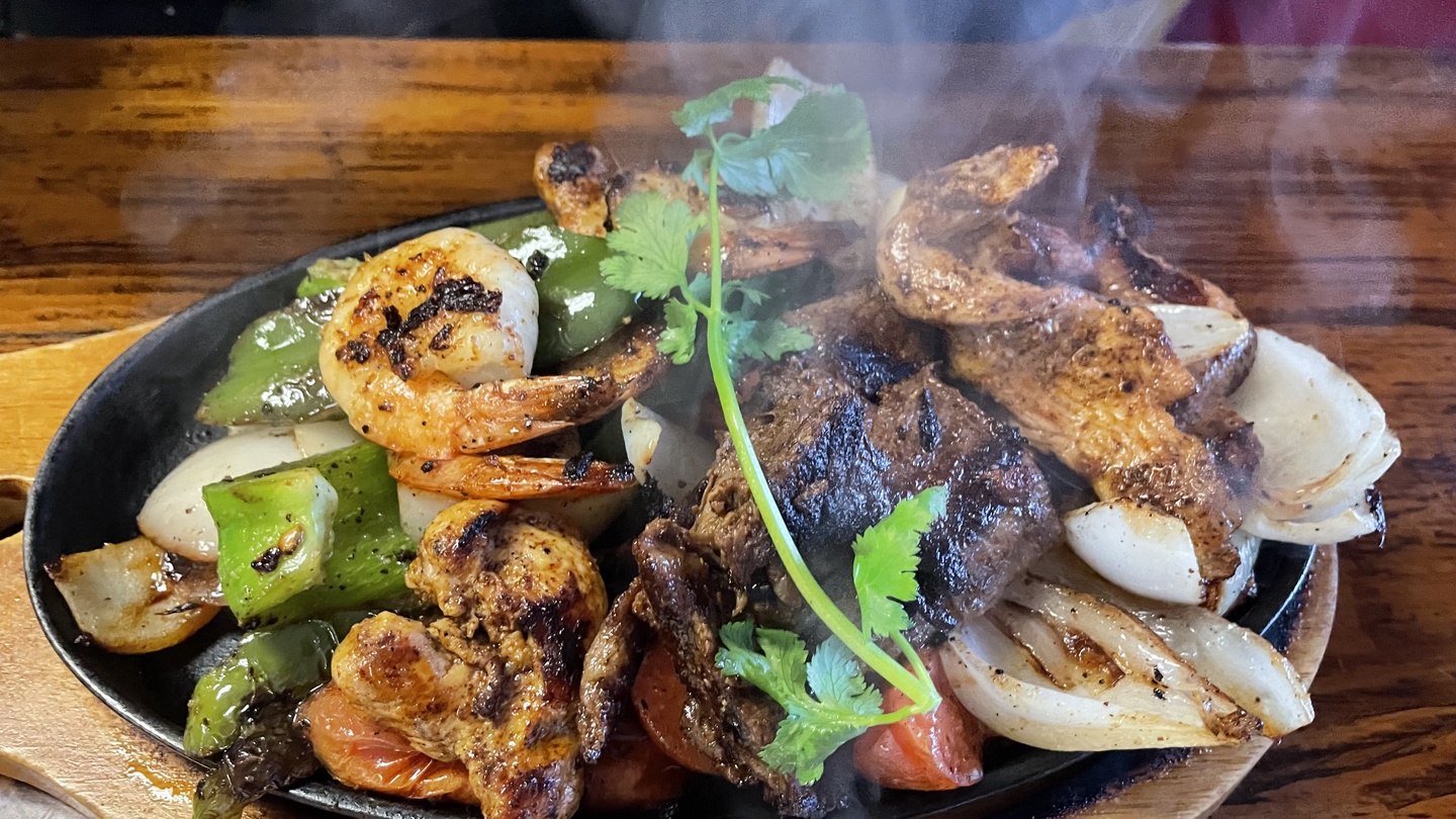 Savor perfectly seared meat and vegetables sizzling on a cast iron plate, delivered steaming hot to your table.