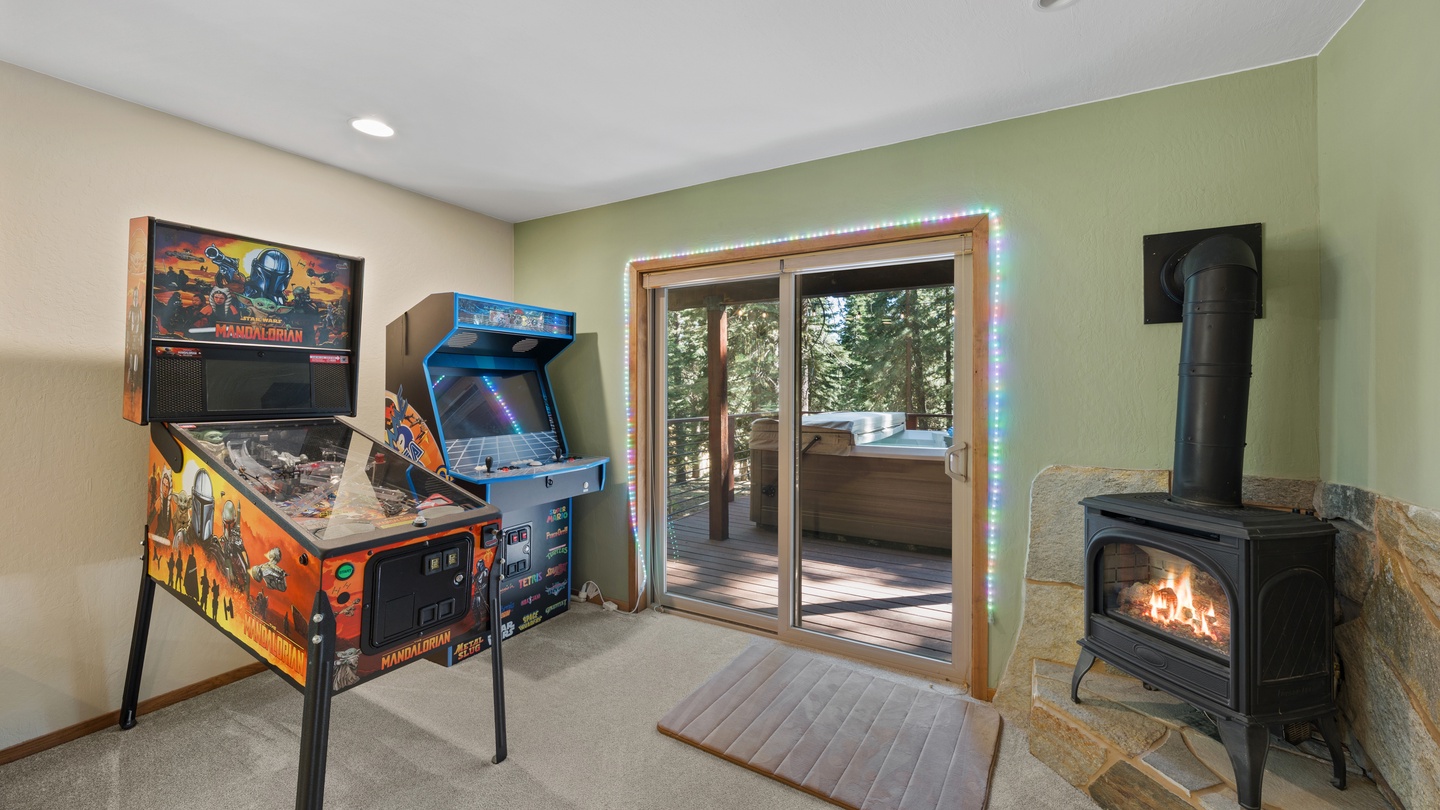 Step into your private game room, where a vintage pinball machine and arcade cabinet await your challenge. Glass doors open to the deck and hot tub, while a cozy fireplace adds warmth to your downtime.