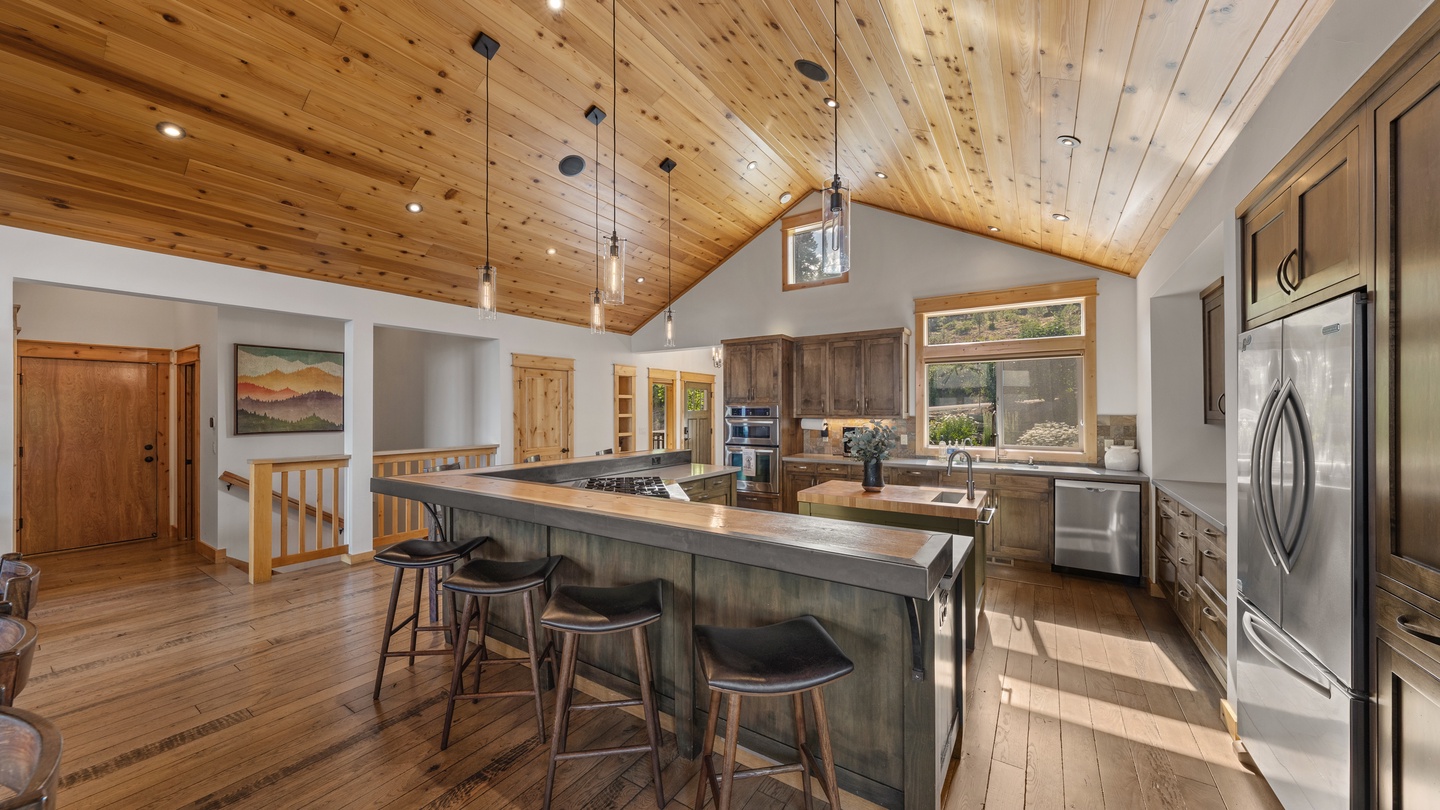 Gather around the spacious kitchen island under soaring wood ceilings, where natural light pours in and modern appliances meet rustic charm—your perfect spot for morning coffee or meal prep.