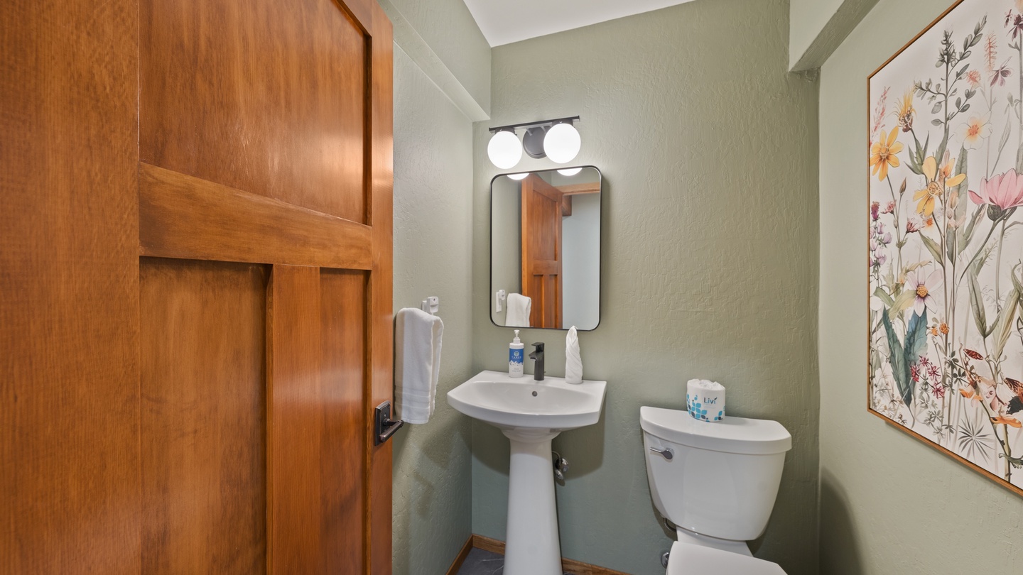 Step into your private powder room, where sage walls and cheerful floral art create a serene start to your mornings. Fresh towels, a modern pedestal sink, and thoughtful touches make this space truly yours.
