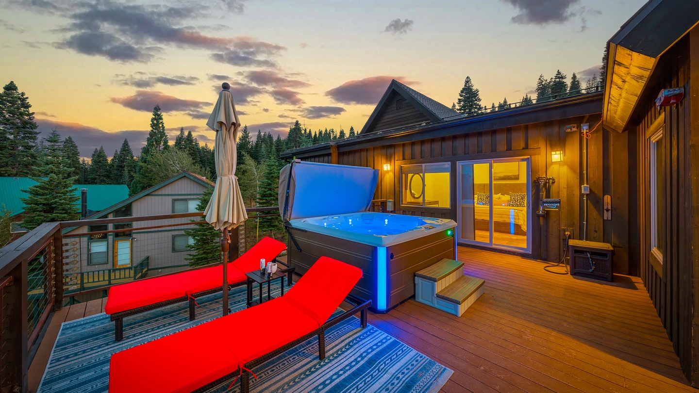 The property sits nestled among towering pines in a peaceful mountain setting, with warm light glowing from within as dusk settles over the surrounding forests and neighboring cabins.