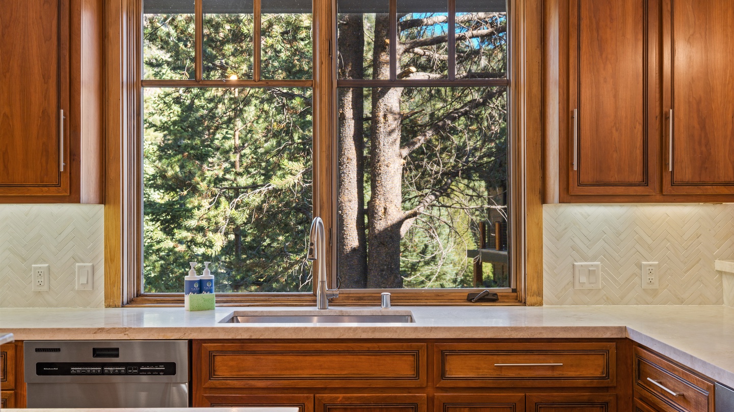Prepare your favorite meals in this well-appointed kitchen surrounded by warm wood cabinetry and scenic forest views through the window.