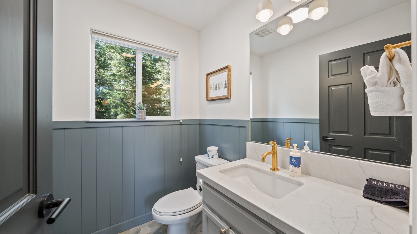 Freshen up in your stylish bathroom with calming blue wainscoting and a peaceful view of the surrounding trees—your fluffy robes and premium toiletries await.