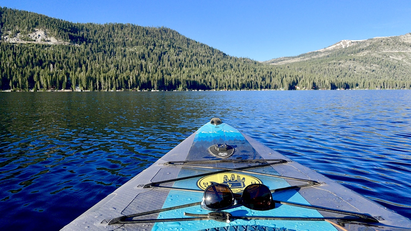 Donner Lake surrounded by dense forests and snow-capped peaks, perfect for kayaking and water activities.