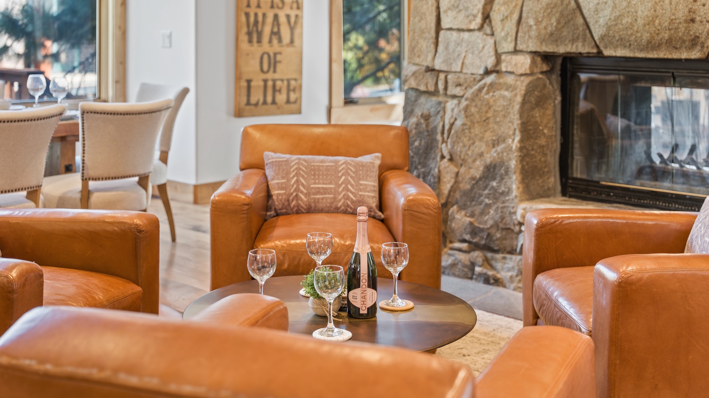 Sink into buttery leather seating by the stone fireplace, where champagne glasses await your evening toast. Large windows frame the greenery outside, making this warm gathering space your home away from home.