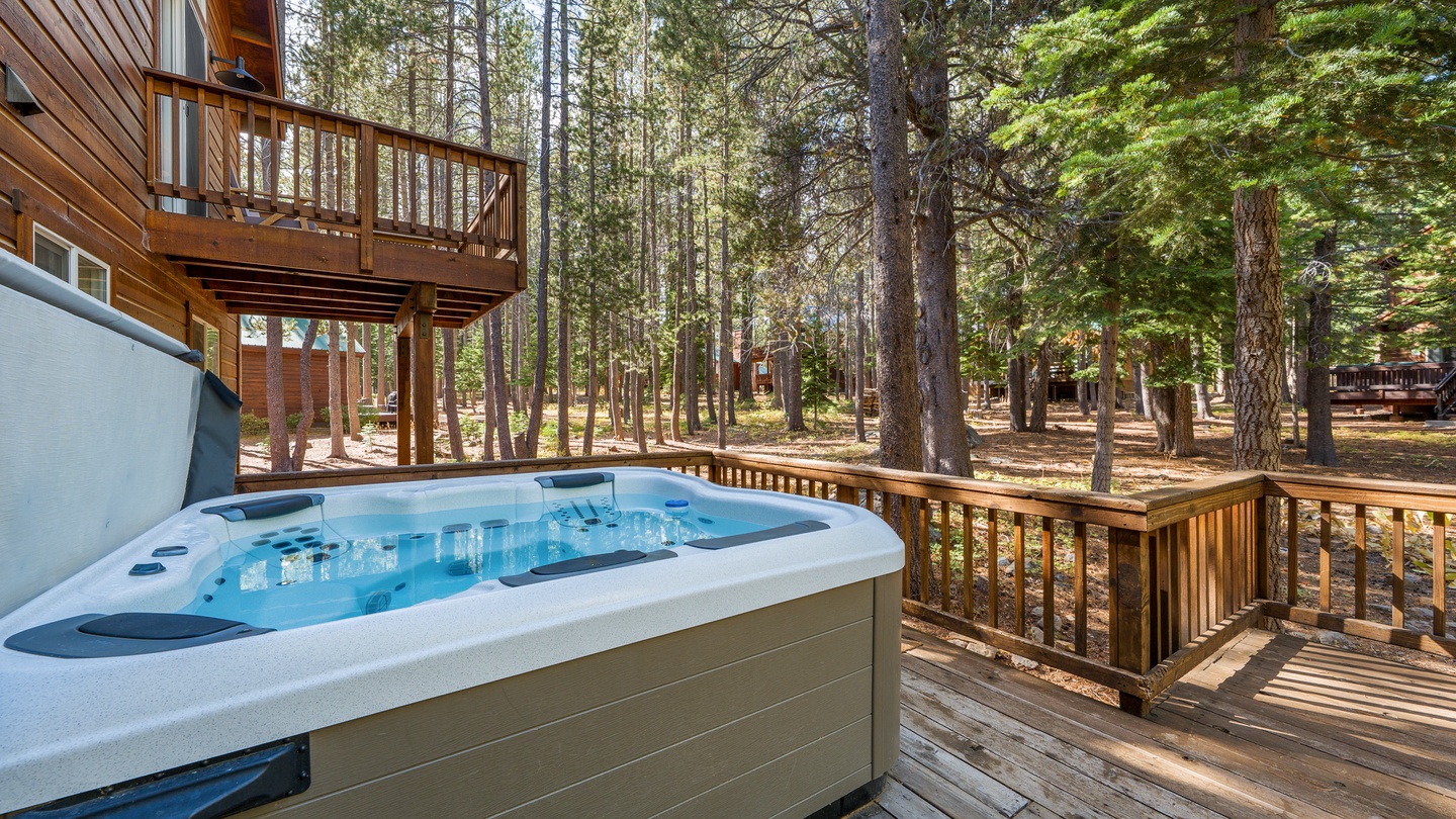 Soak in your private hot tub on the spacious deck, surrounded by towering pines and tranquil forest views that create a peaceful, secluded retreat.