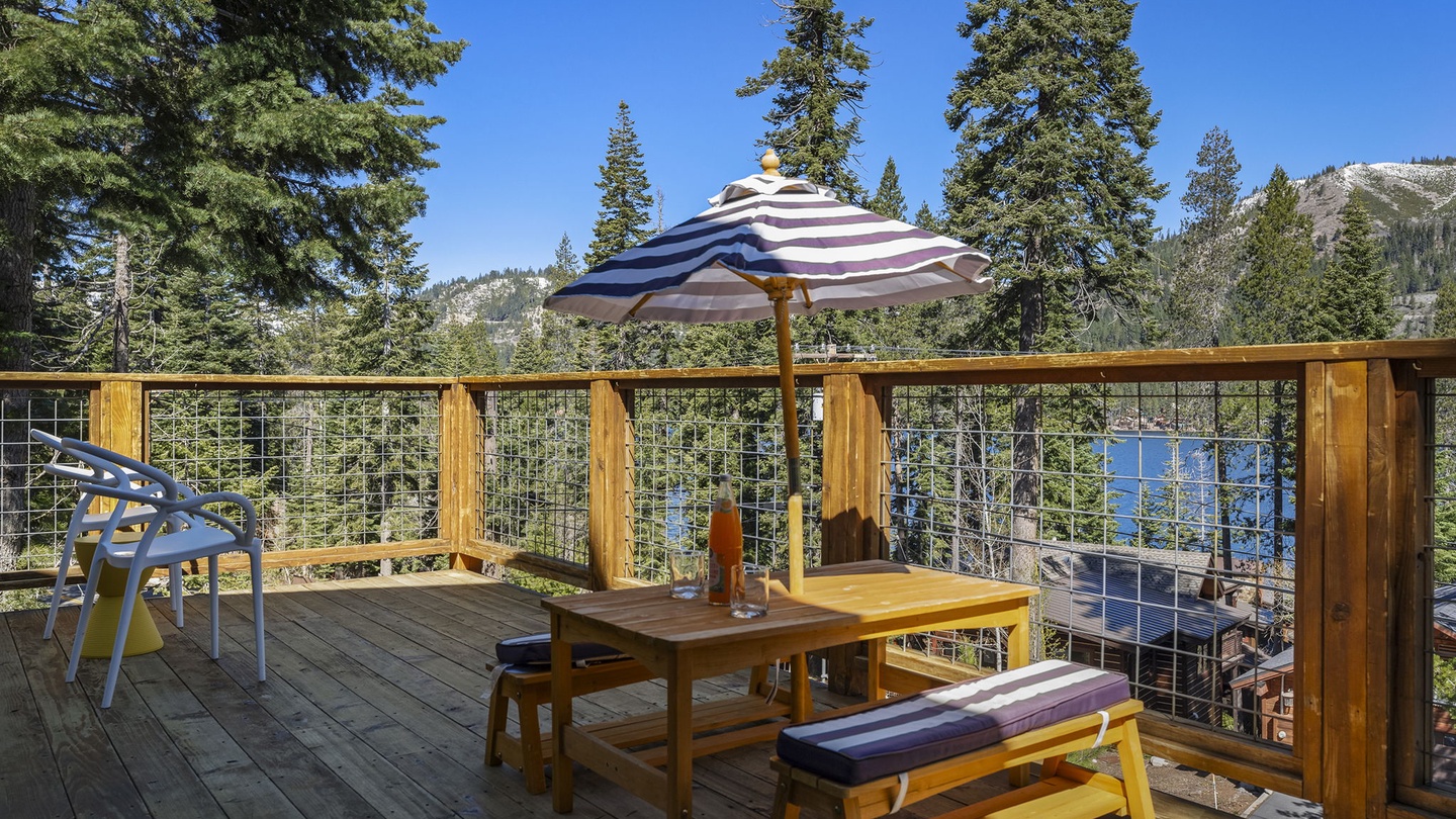Your private deck showcases breathtaking mountain and lake vistas, perfect for morning coffee under the striped umbrella.