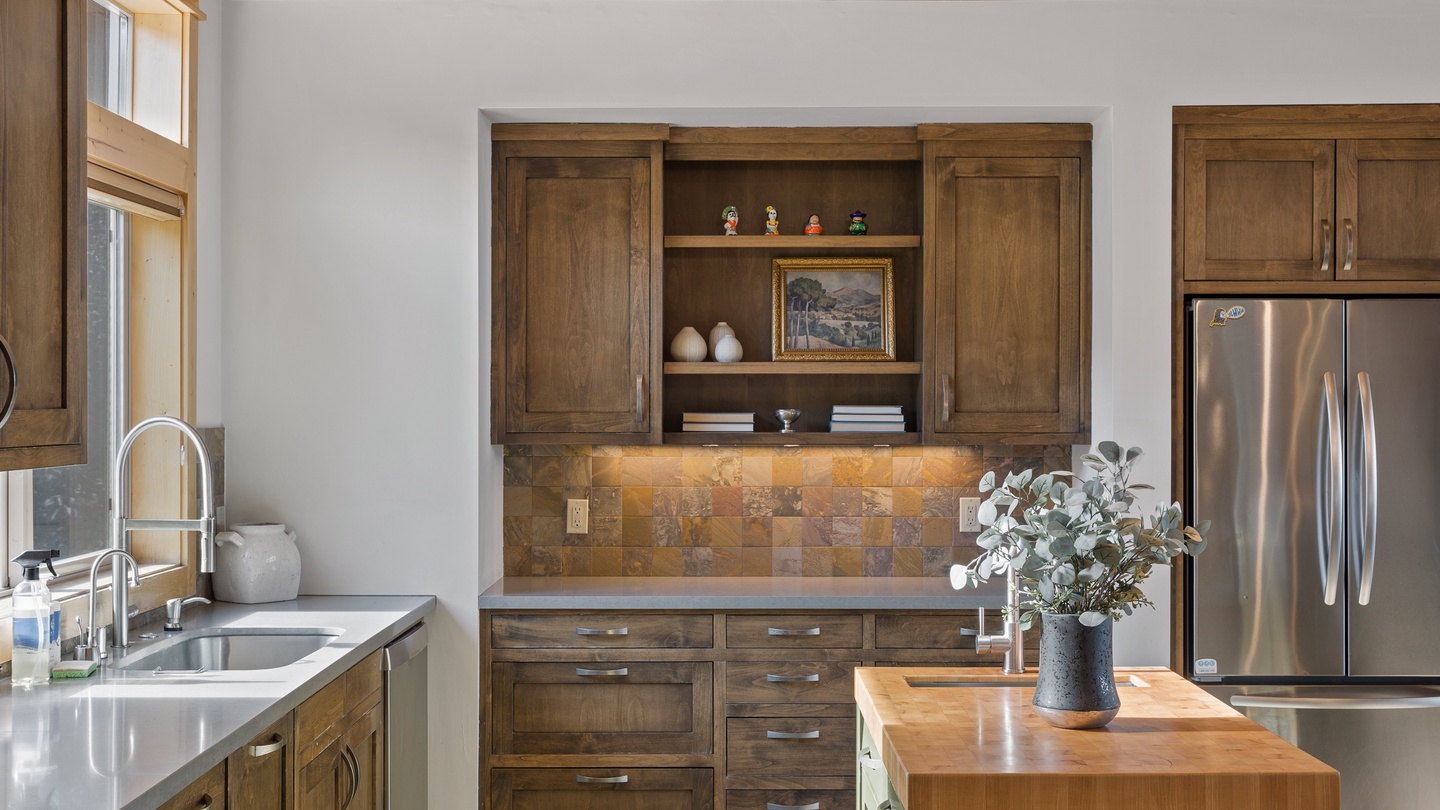 Warm wood cabinetry and natural stone accents create a welcoming kitchen where you can easily prepare meals and gather around the butcher-block island. Enjoy the bright natural light and rustic charm of this inviting space.