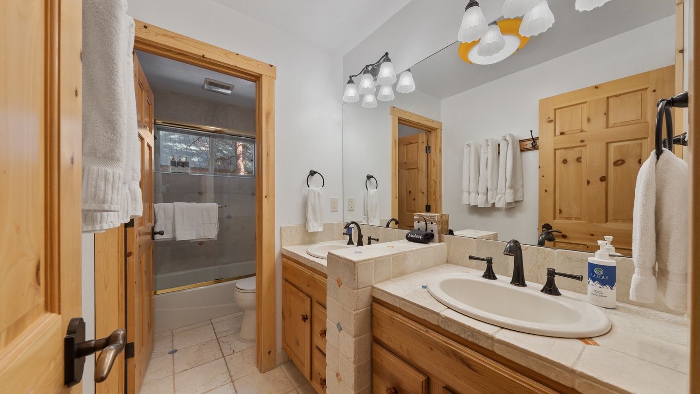 Freshen up in your private bathroom, complete with dual sinks, a walk-in shower, and fluffy towels—all set for your mountain getaway.