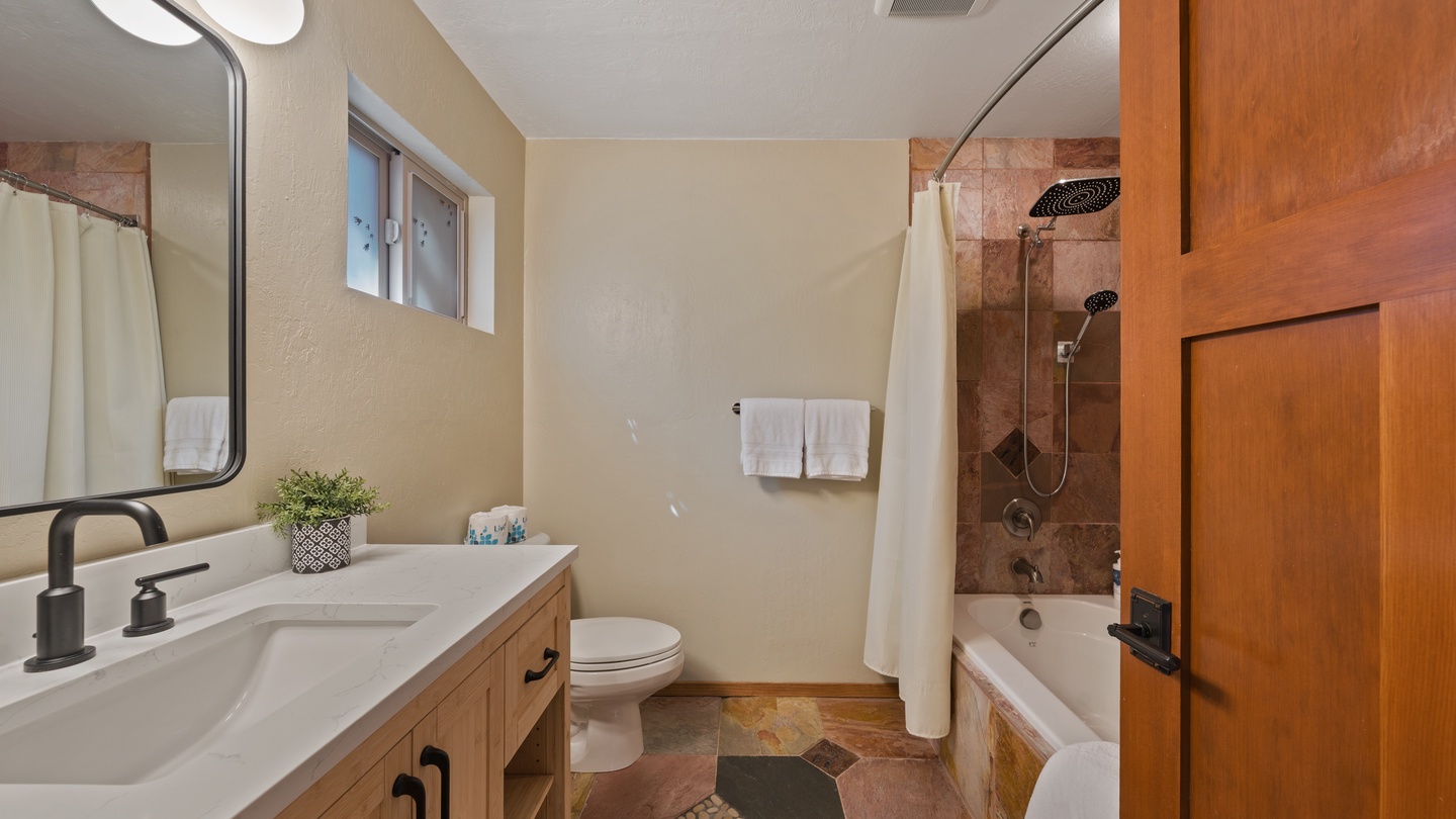 Step into your private spa-like bathroom with rustic stone tile, a soothing tub-shower combo, and warm wood accents that make every refresh feel like a retreat.