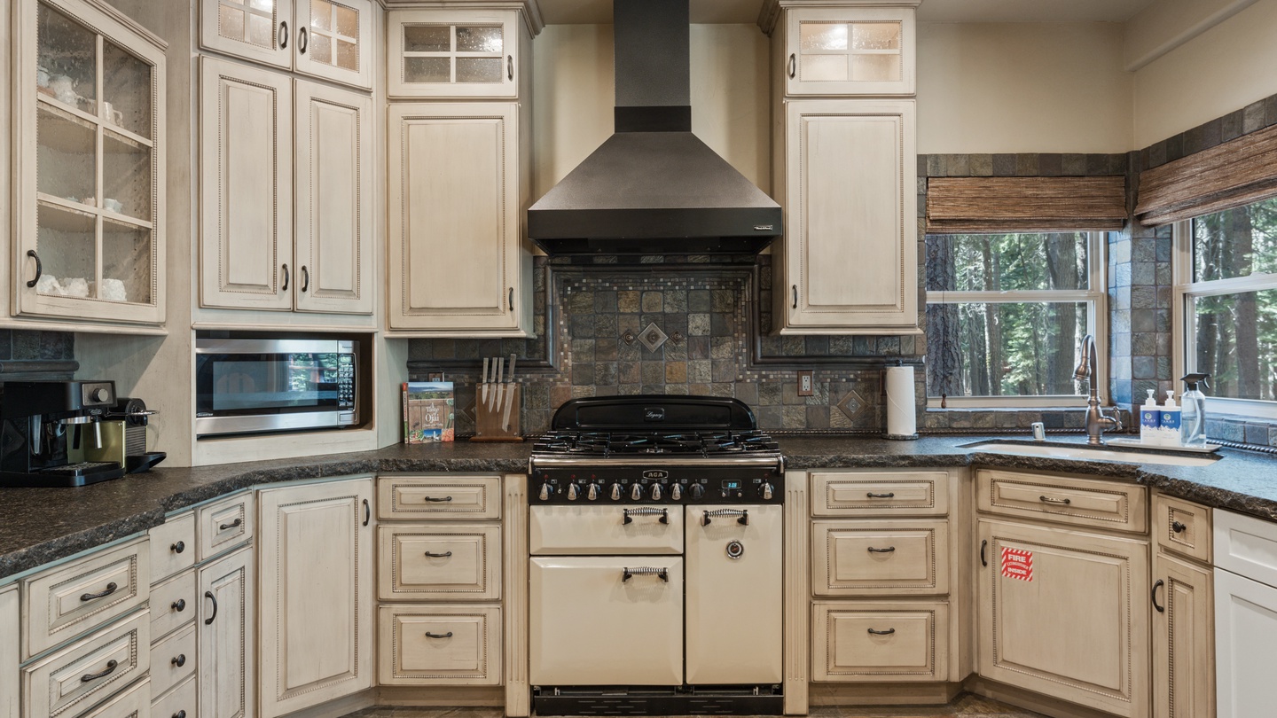 Your gourmet kitchen awaits with vintage-style appliances, elegant cabinetry, and forest views through every window—perfect for creating memorable meals during your stay.