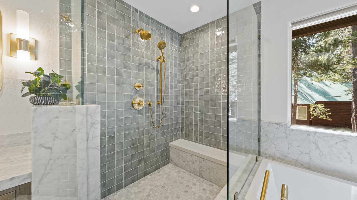 Step into a spa-like sanctuary with elegant marble accents, soothing sage tile, and gleaming gold fixtures that invite you to unwind in style.