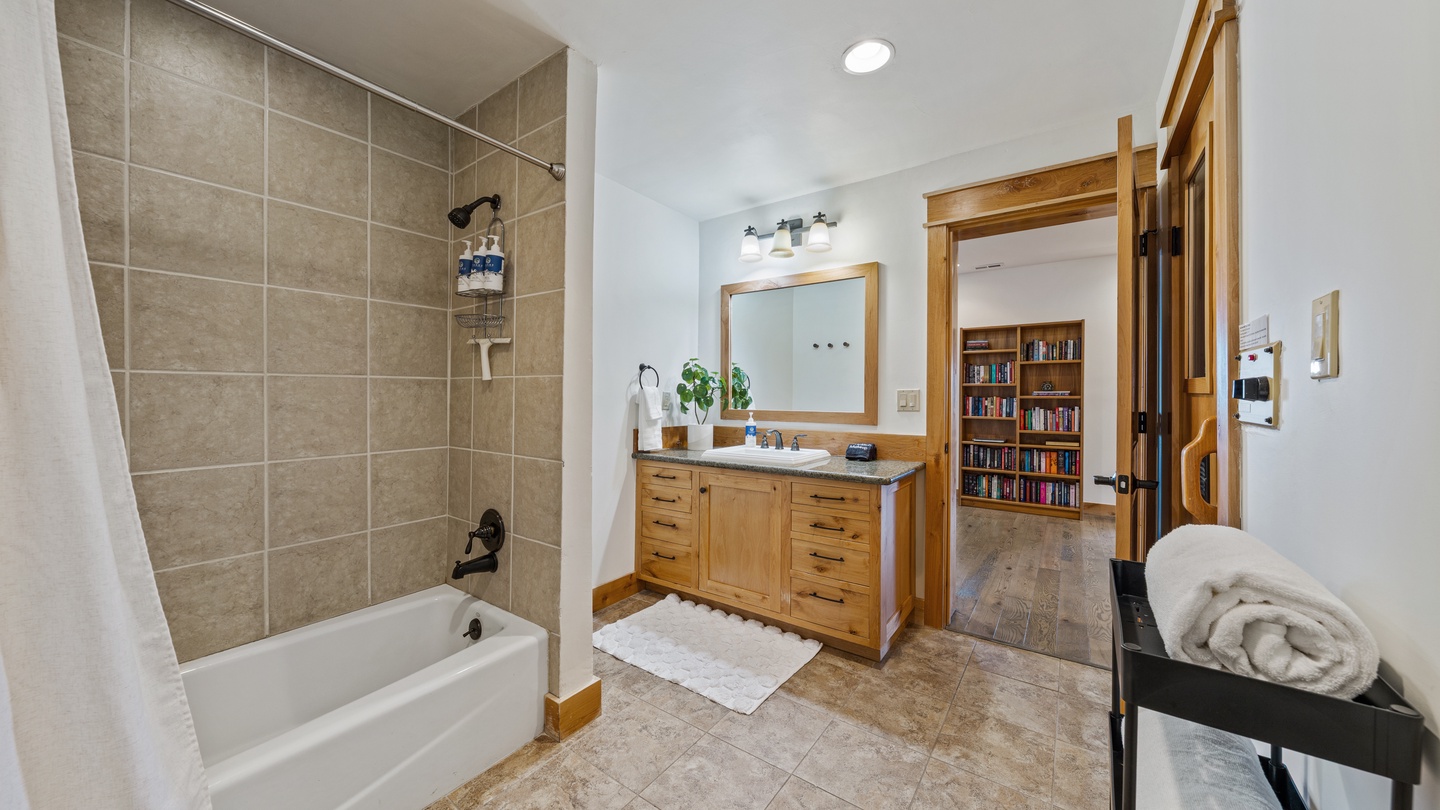 Refresh in your private bathroom with its spacious tub-shower combo, warm wood vanity, and fresh towels waiting for you—a clean, comfortable retreat after exploring the area.