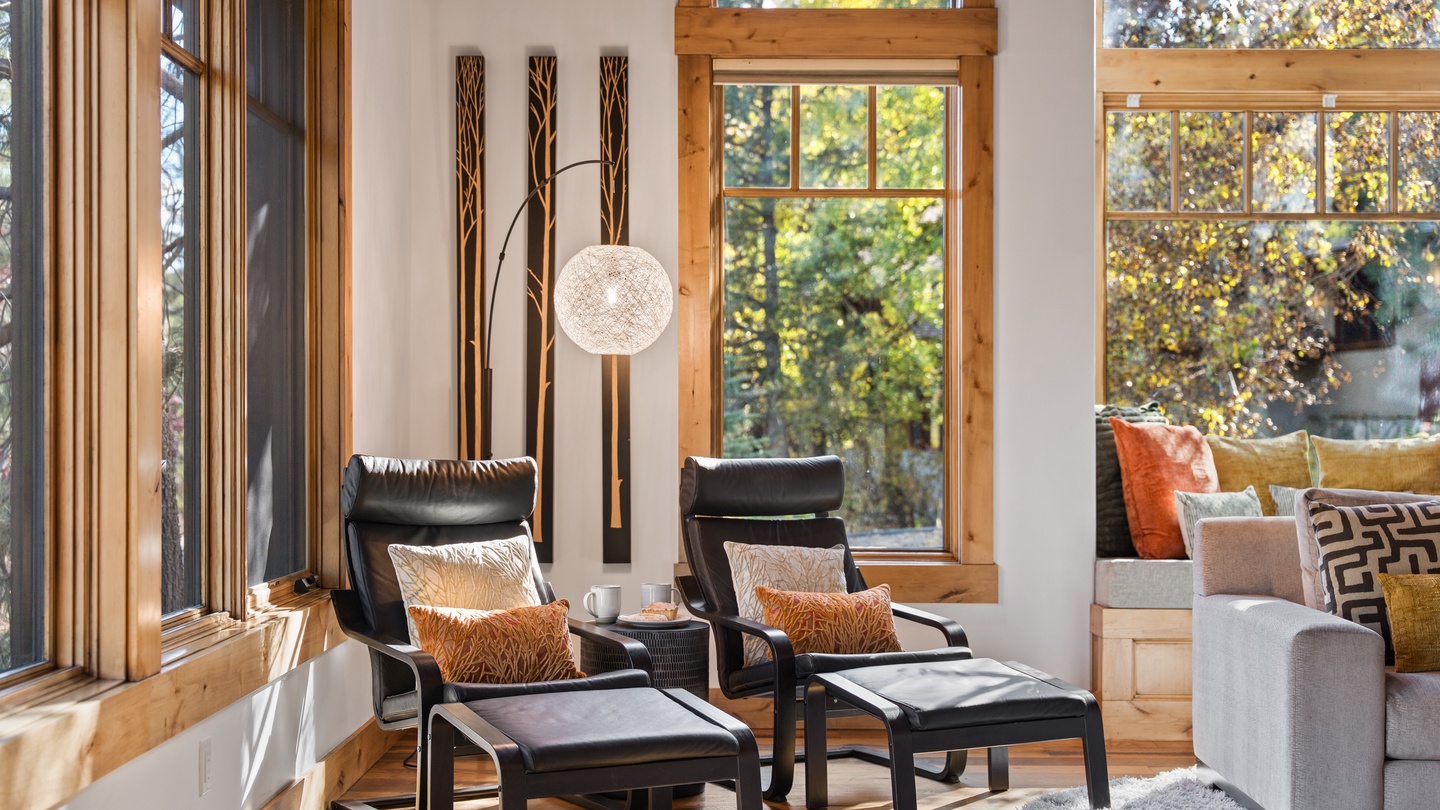 Sink into plush leather recliners with ottomans, where sunlight streams through soaring windows and warm wood frames your peaceful retreat.