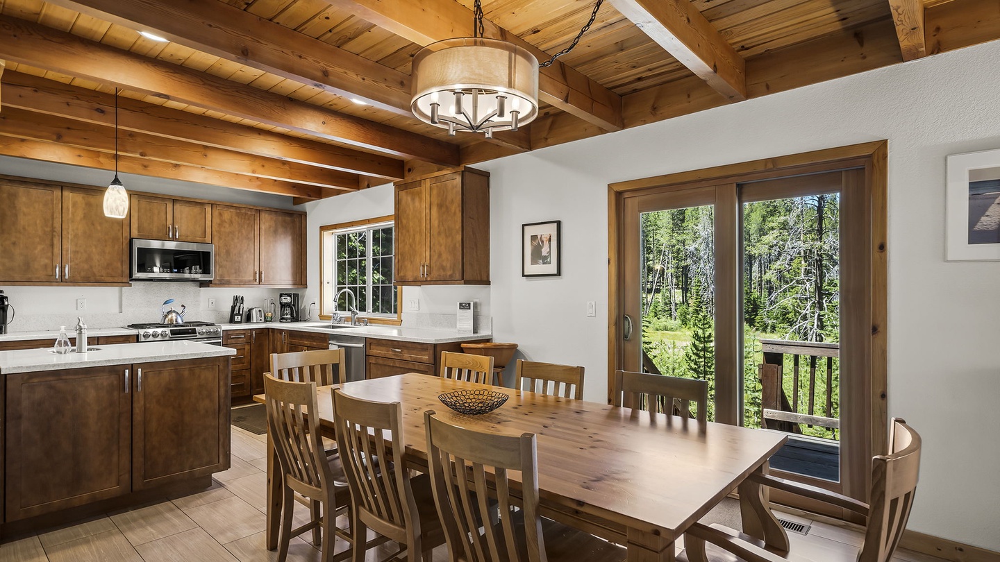 Gather around the rustic wooden table under vaulted beamed ceilings where natural light pours through glass doors. Private deck views of lush forest make every meal feel like an escape.