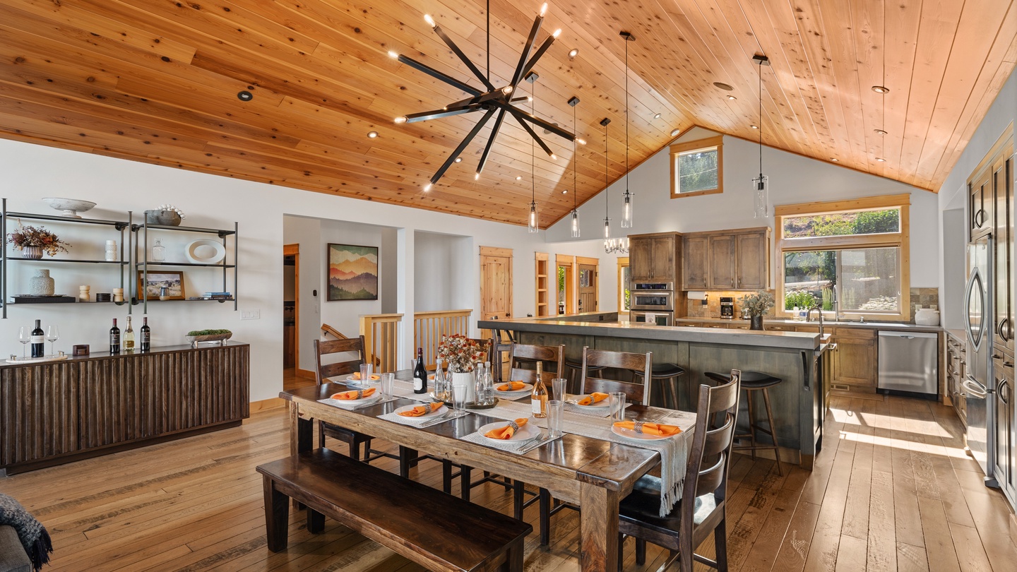 Gather around the handcrafted dining table beneath soaring wood ceilings, where natural light pours through cathedral windows and the open kitchen invites you to cook and connect with your group.