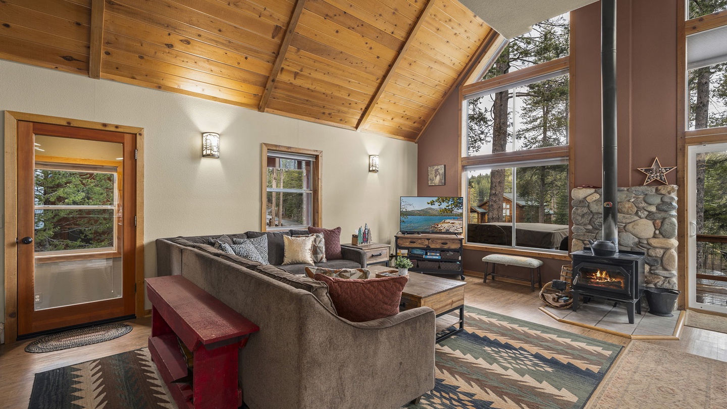 Unwind in your spacious living room with soaring wood-beam ceilings, cozy fireplace, and floor-to-ceiling windows framing forest views.