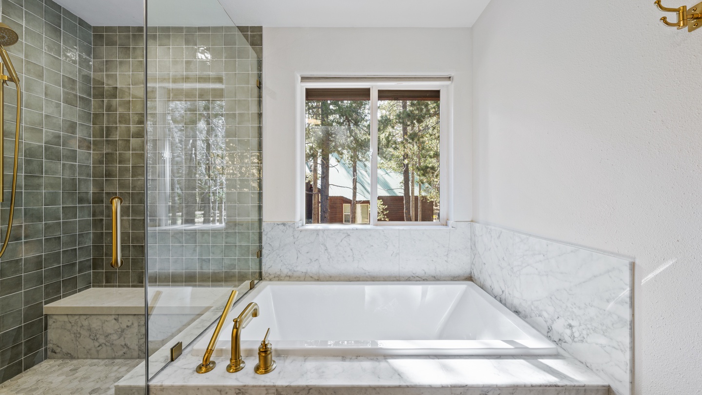 Soak away your cares in your elegant soaking tub, framed by marble and offering peaceful tree views through the window—a serene retreat after a day of adventure.