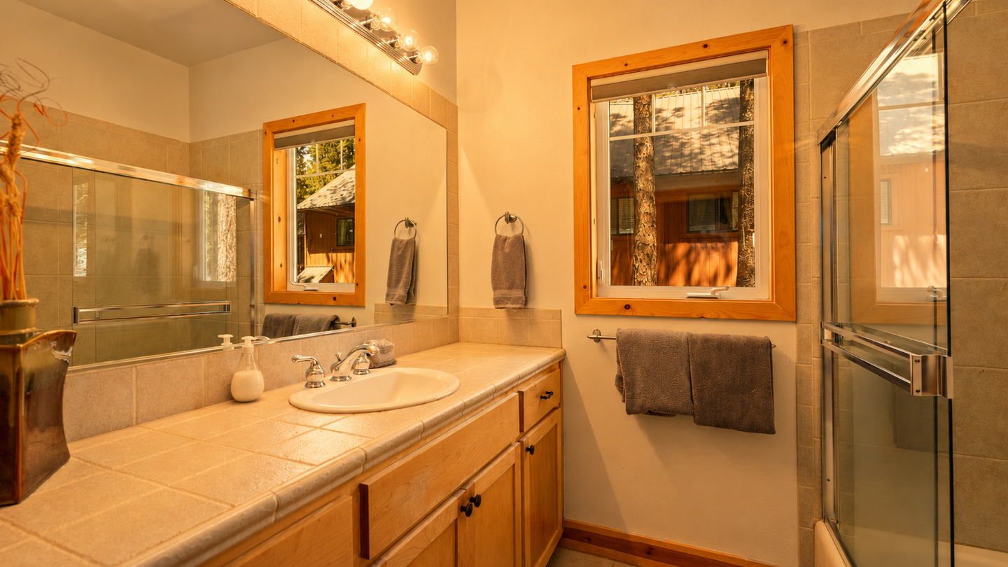 Freshen up in your private bathroom, featuring warm wood accents, ample counter space, and a walk-in shower. Soft lighting and forest views create a peaceful, spa-like retreat after a day of adventure.