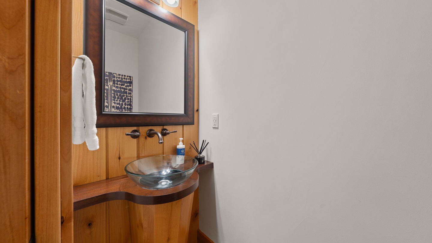 Freshen up at your stylish vanity with warm wood tones and a glass vessel sink, where fluffy towels and thoughtful details await your arrival.
