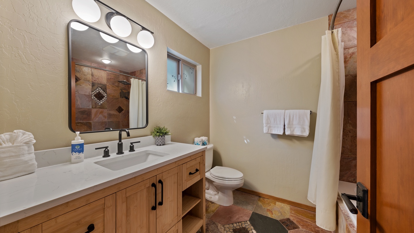 Step into your private spa-like retreat with warm tile floors, a spacious vanity, and a refreshing walk-in shower behind that elegant curtain.