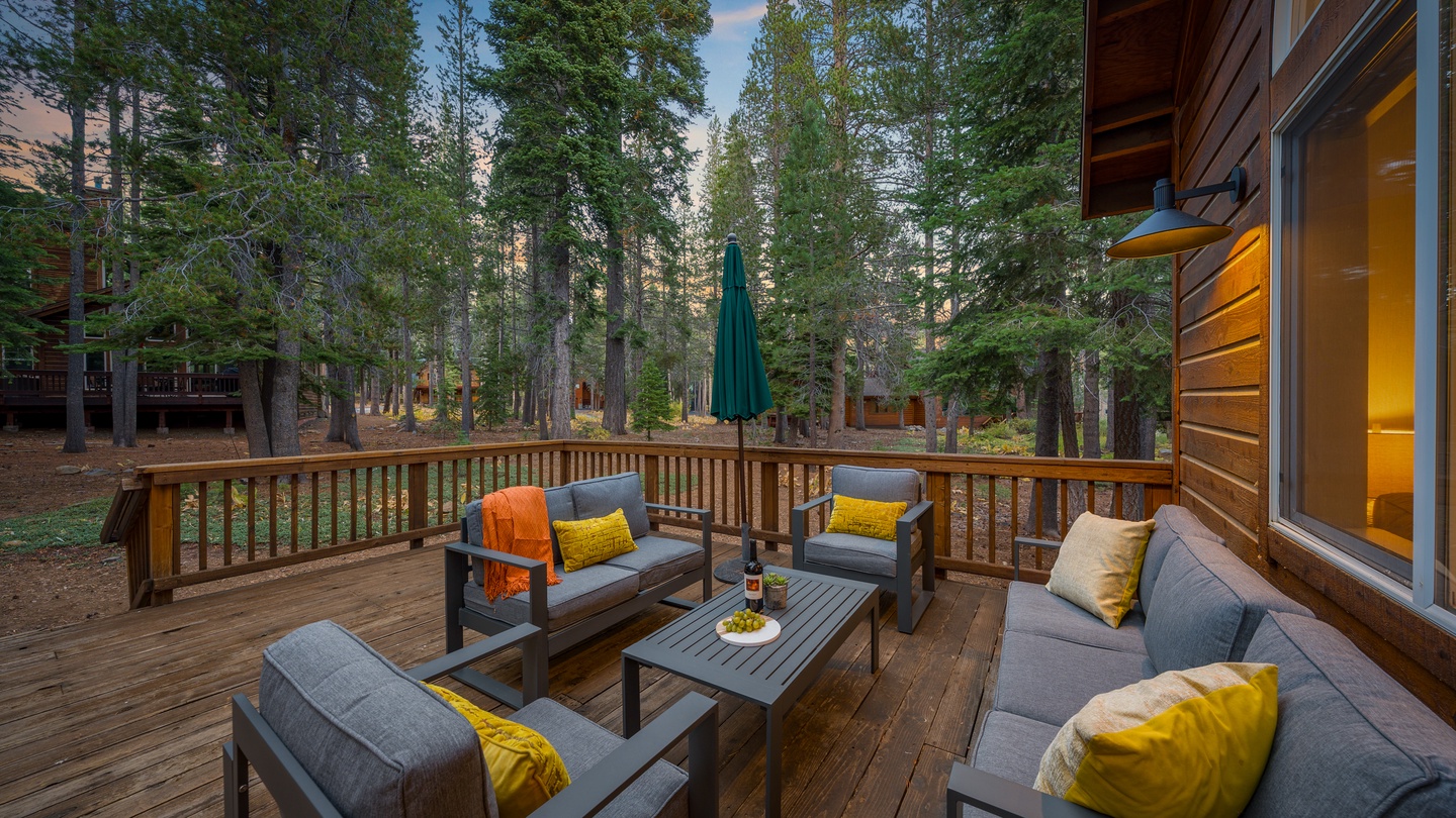 Unwind on your private deck surrounded by towering pines, with plush seating and warm sunset light filtering through the trees—perfect for evening relaxation and taking in the peaceful forest atmosphere.