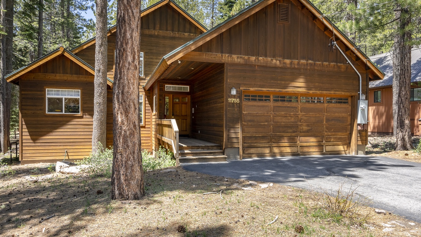 A secluded wood-sided retreat nestled among towering pines, offering a peaceful mountain escape with convenient driveway parking and a charming, welcoming entrance.