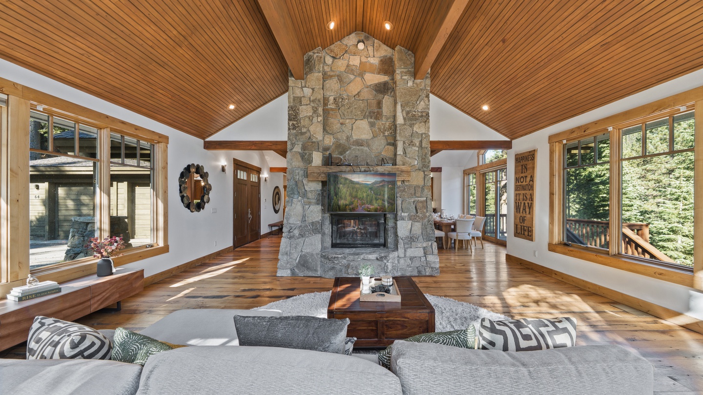 You'll love gathering in this stunning open-concept living space, where soaring wood ceilings and a dramatic stone fireplace create a warm, luxurious mountain retreat perfect for relaxing with friends and family.
