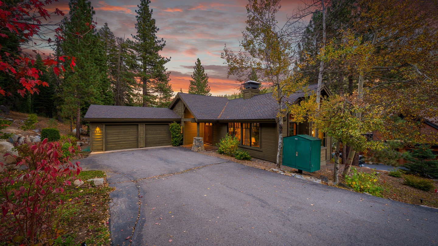 A beautifully appointed mountain retreat nestled among towering pines, captured during a stunning autumn sunset. The warm glow from the windows invites you to settle in after a day exploring the surrounding forests and trails.
