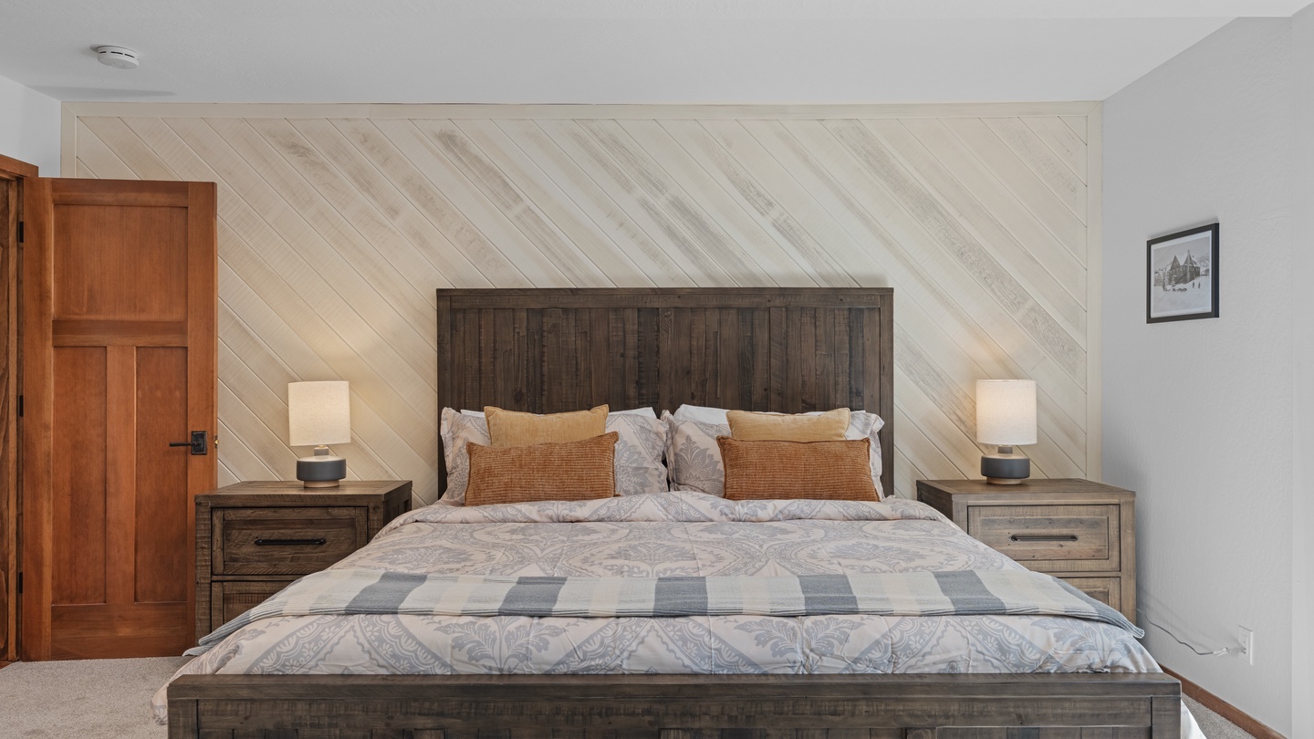 Drift off in this serene bedroom with its rustic wood furnishings, soft ambient lighting, and thoughtful décor. The inviting bed promises restful nights, while the diagonal accent wall adds modern charm to your peaceful mountain retreat.