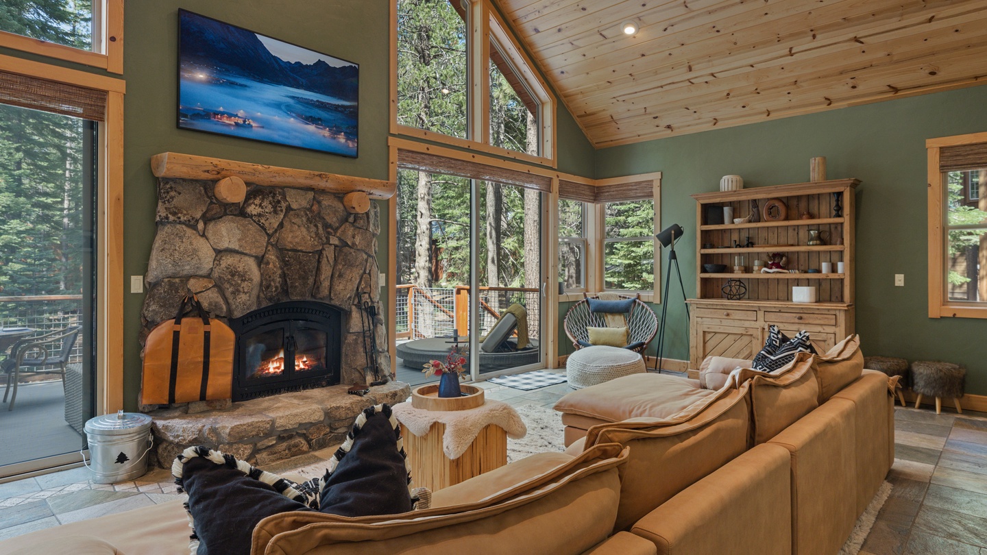 Unwind by the crackling fireplace in this cozy living room, where towering windows frame the surrounding forest. Sink into plush leather seating and let the warmth of natural wood and stone wrap around you.
