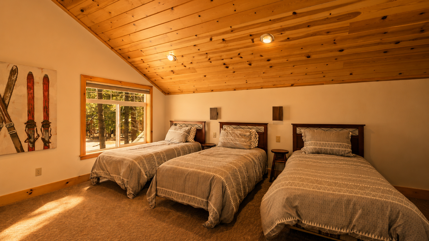 Wake up refreshed in this cozy bedroom featuring three comfortable beds, warm knotty pine ceilings, and soft natural light streaming through the window. Perfect for families or groups sharing mountain memories.