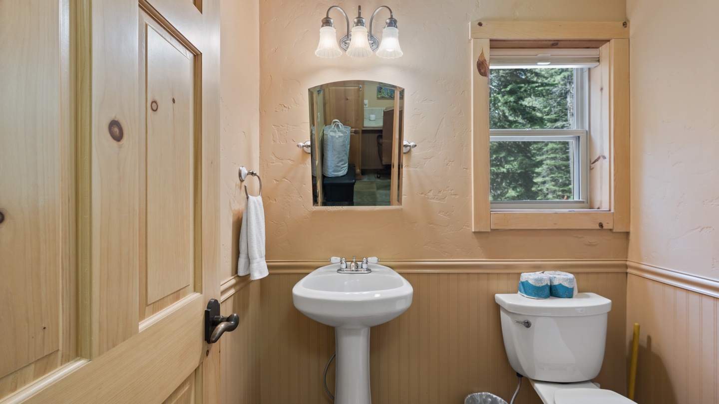 Charming bathroom with natural light from the window, classic pedestal sink, and fresh towels ready for your arrival.