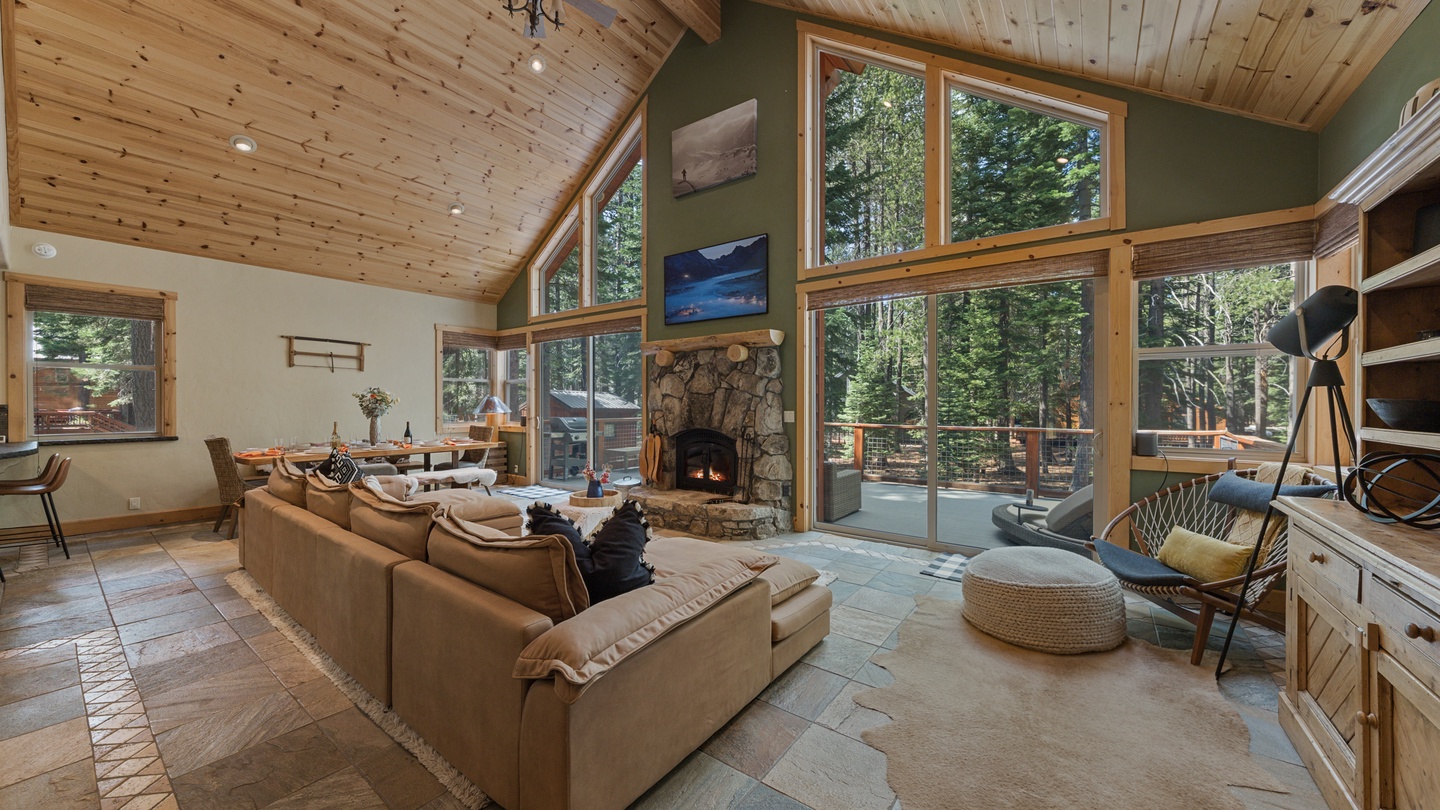 Sink into the plush sofa by your private stone fireplace while soaring vaulted ceilings and floor-to-ceiling windows frame a stunning forest view, creating the ultimate mountain retreat for your relaxation.