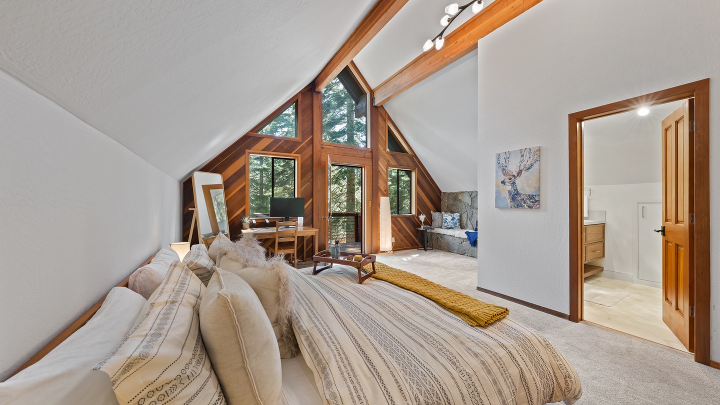 Wake up in a stunning loft bedroom with soaring cathedral ceilings and warm wood beams framing peaceful forest views. The vaulted design and natural light create an airy, restful retreat just for you.