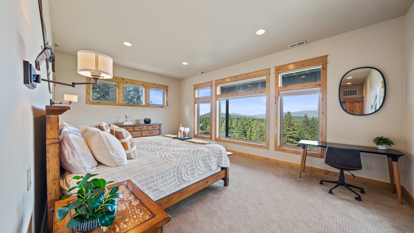 Wake up to sweeping forest views from this serene bedroom retreat. Sunlight pours through tall windows, framing a peaceful panorama that makes every morning feel special.