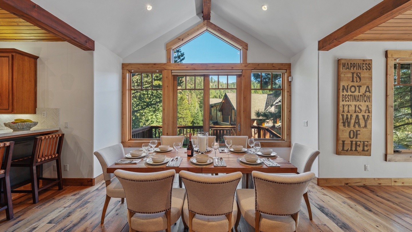 Gather around this beautiful dining table beneath soaring vaulted ceilings and warm wood accents. Windows frame lush forest views, bringing the outdoors right to your seat for memorable meals together.