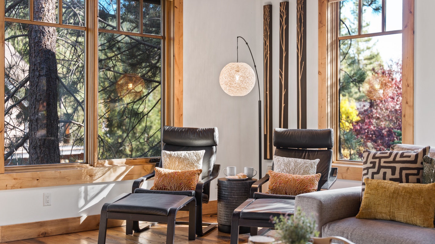 Sink into sleek loungers and unwind in a sun-drenched space where floor-to-ceiling windows frame tranquil forest views. Natural wood and modern design blend seamlessly for your ultimate relaxation.