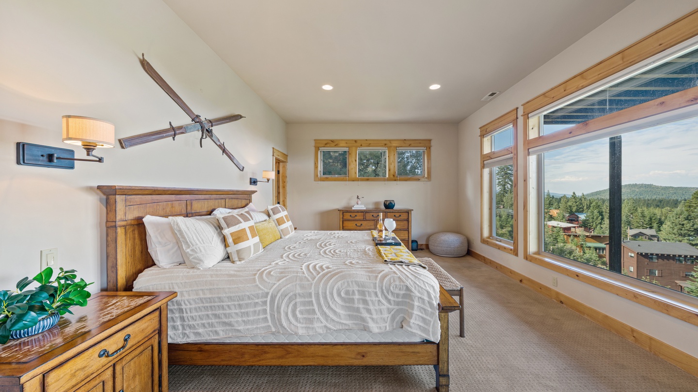 Wake up to sweeping mountain and forest views framed by warm wood windows. Your peaceful retreat features vaulted ceilings, cozy bedding, and natural light that fills the room all day.