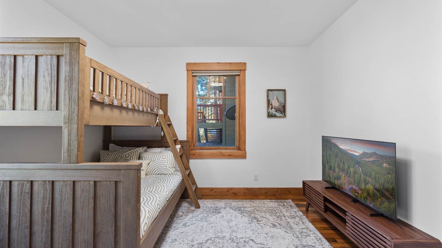 Your kids will love this cozy bunk room, designed for rest and play with rustic wood furnishings, soft linens, and a TV for movie nights together.