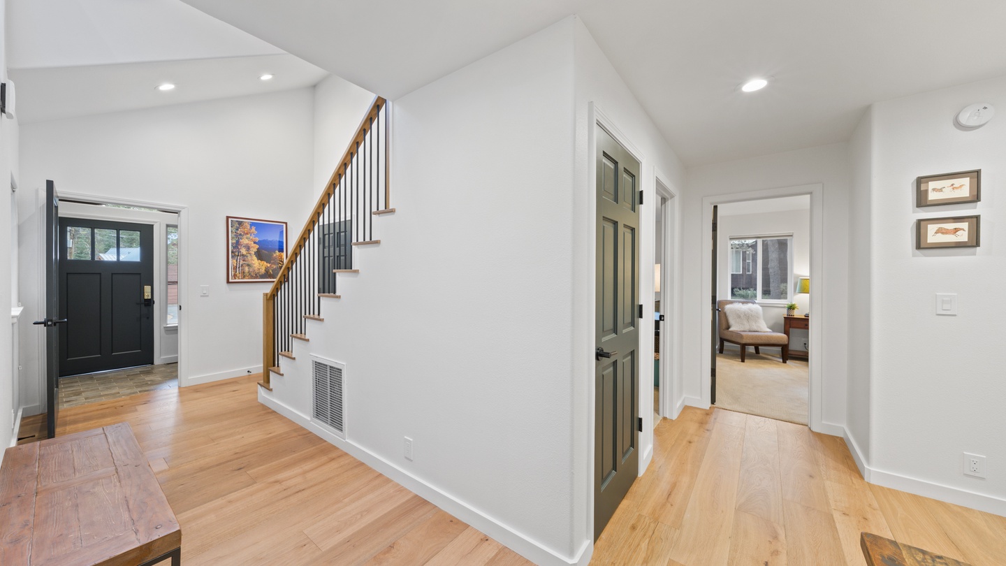 Step into a bright, open entryway with soaring vaulted ceilings and warm wood floors that flow throughout. Your stairway leads to private spaces above, while inviting rooms await just beyond.