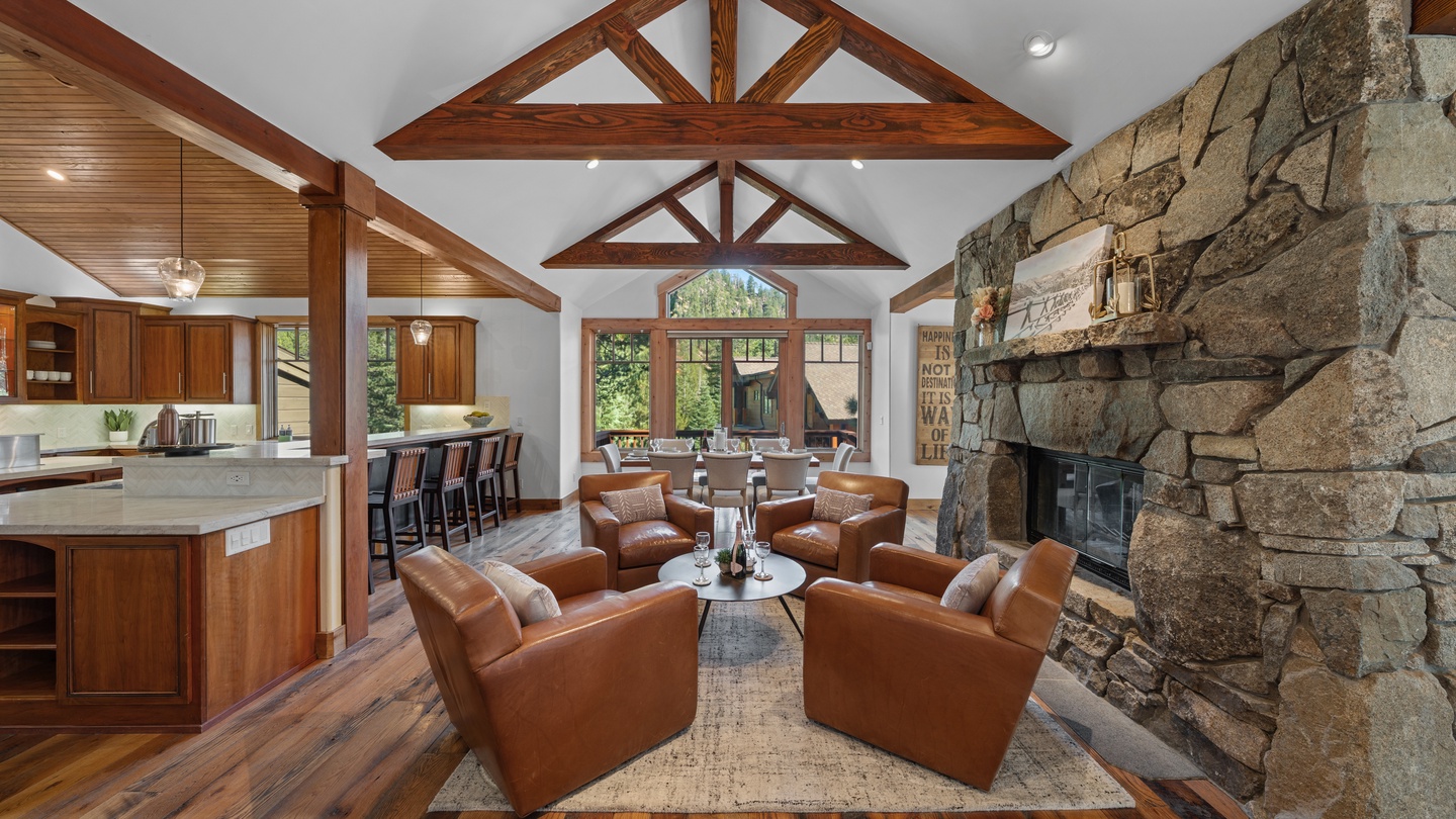 Relax into plush leather seating beneath soaring timber beams, where the warmth of the stacked stone fireplace invites you to unwind in this airy, open-plan living space.