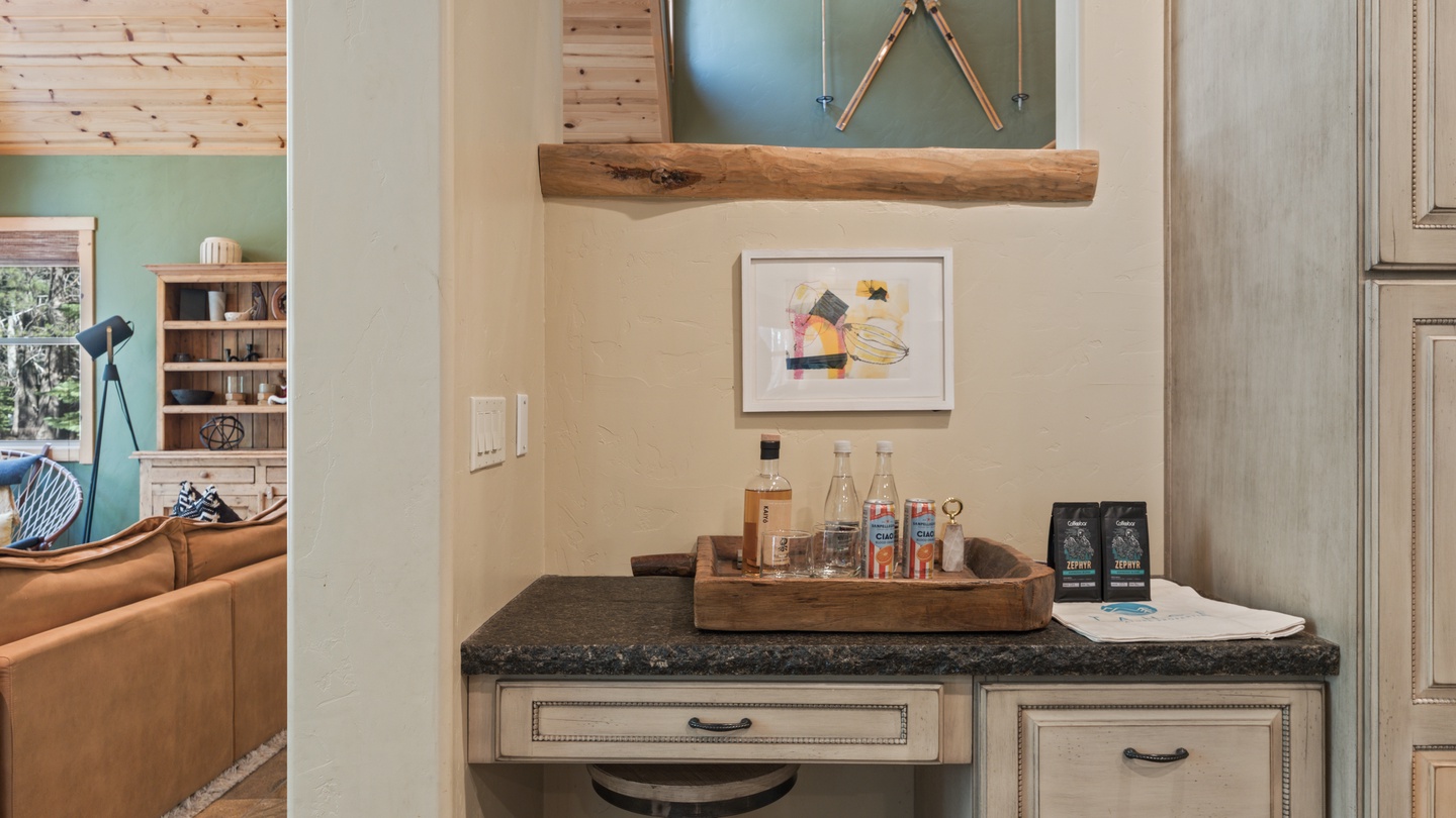 Your private refreshment station awaits with curated spirits and coffee, tucked into a cozy nook beneath rustic wood beams and thoughtful mountain-inspired décor.