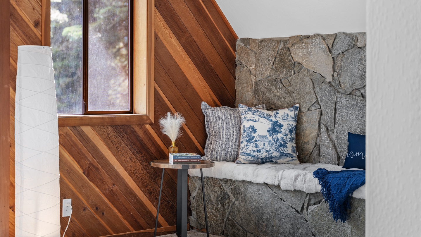 Curl up in this charming reading nook with its cozy stone bench, soft pillows, and natural light—your perfect retreat for quiet moments.